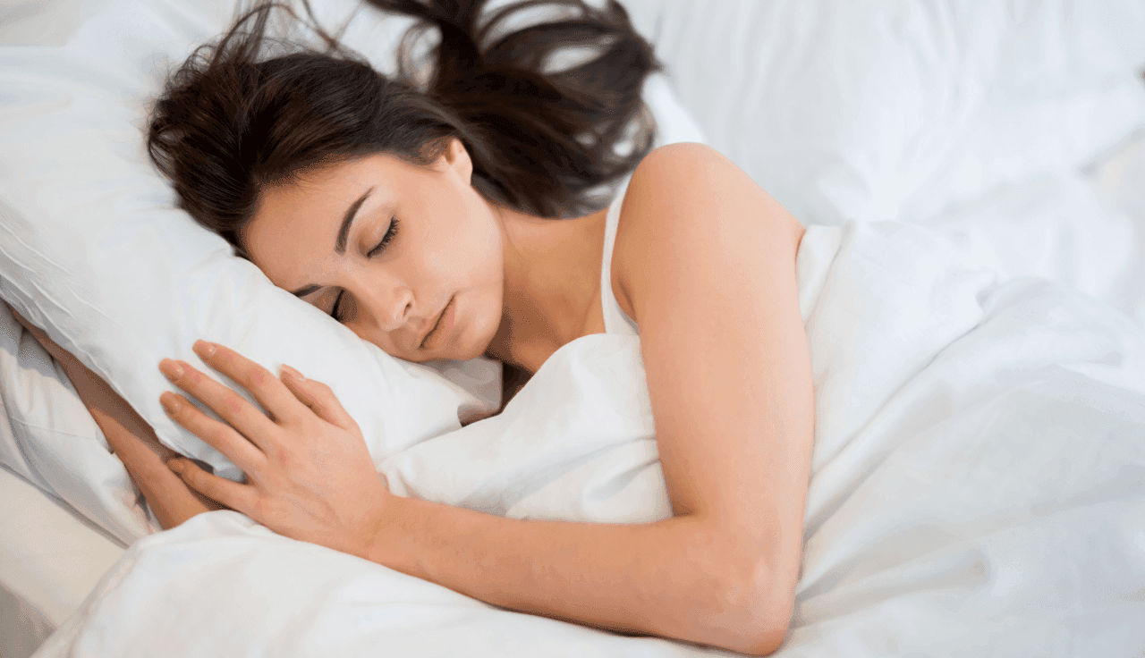 Frau liegt im Bett zur Seite gedreht und schläft