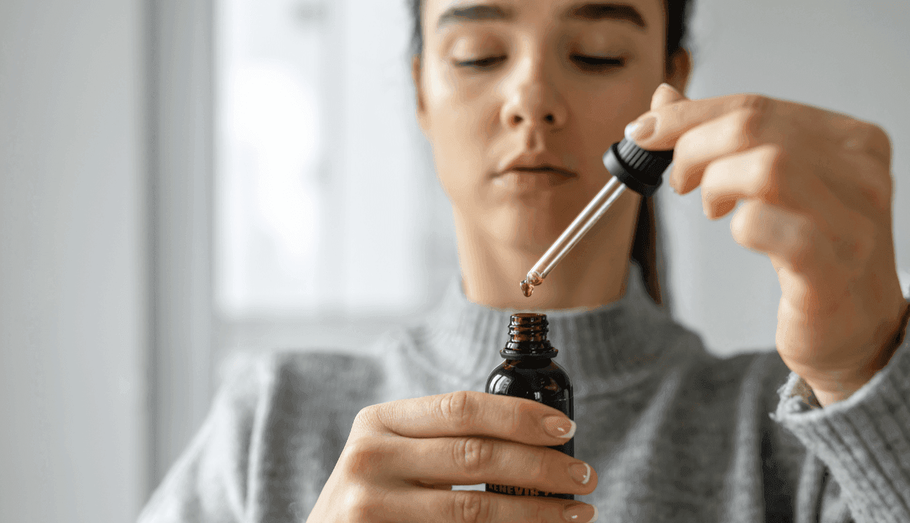 Frau hält ein Glas und eine Pipette in der Hand